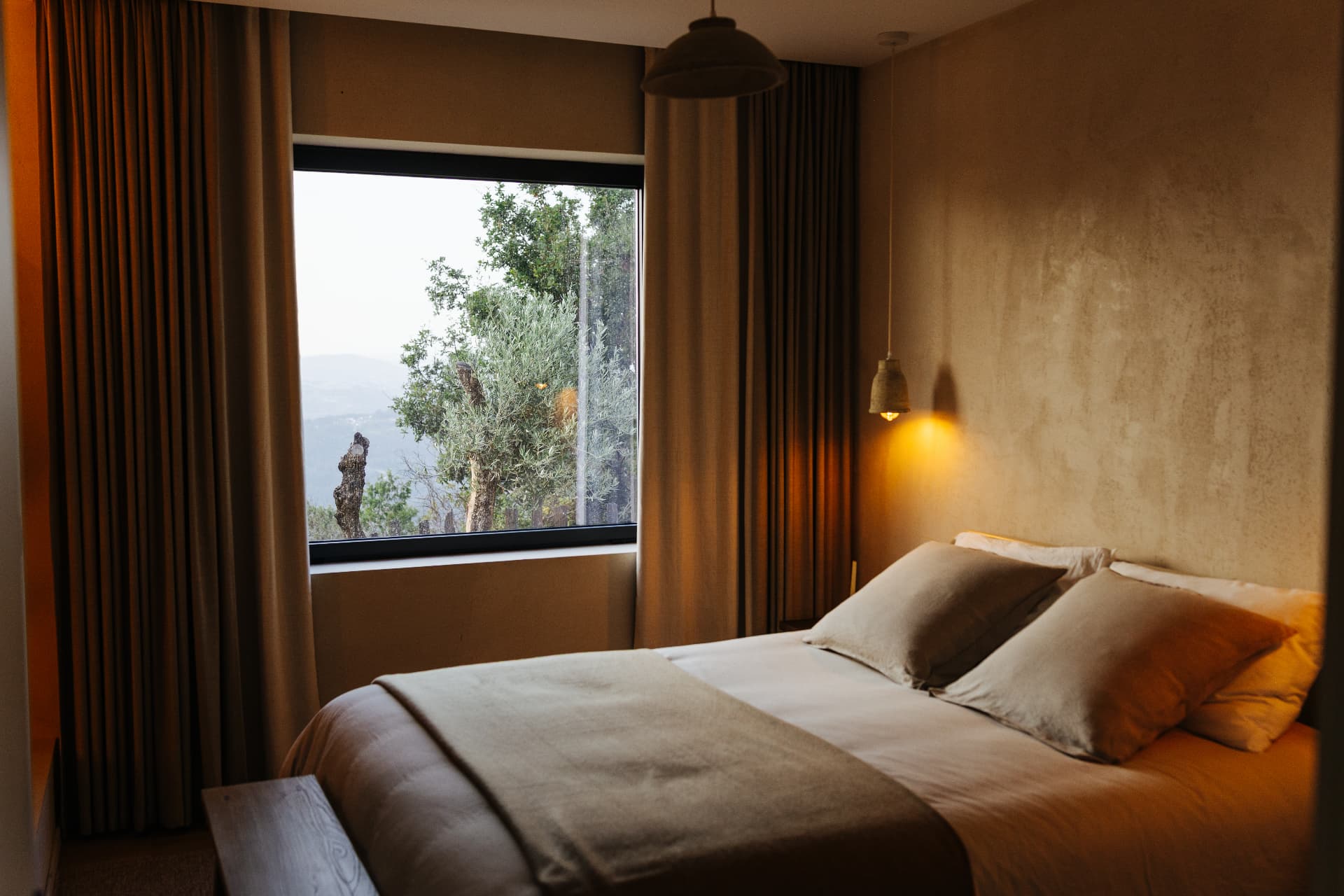 Warmly lit bedroom with earthy textures and a valley view