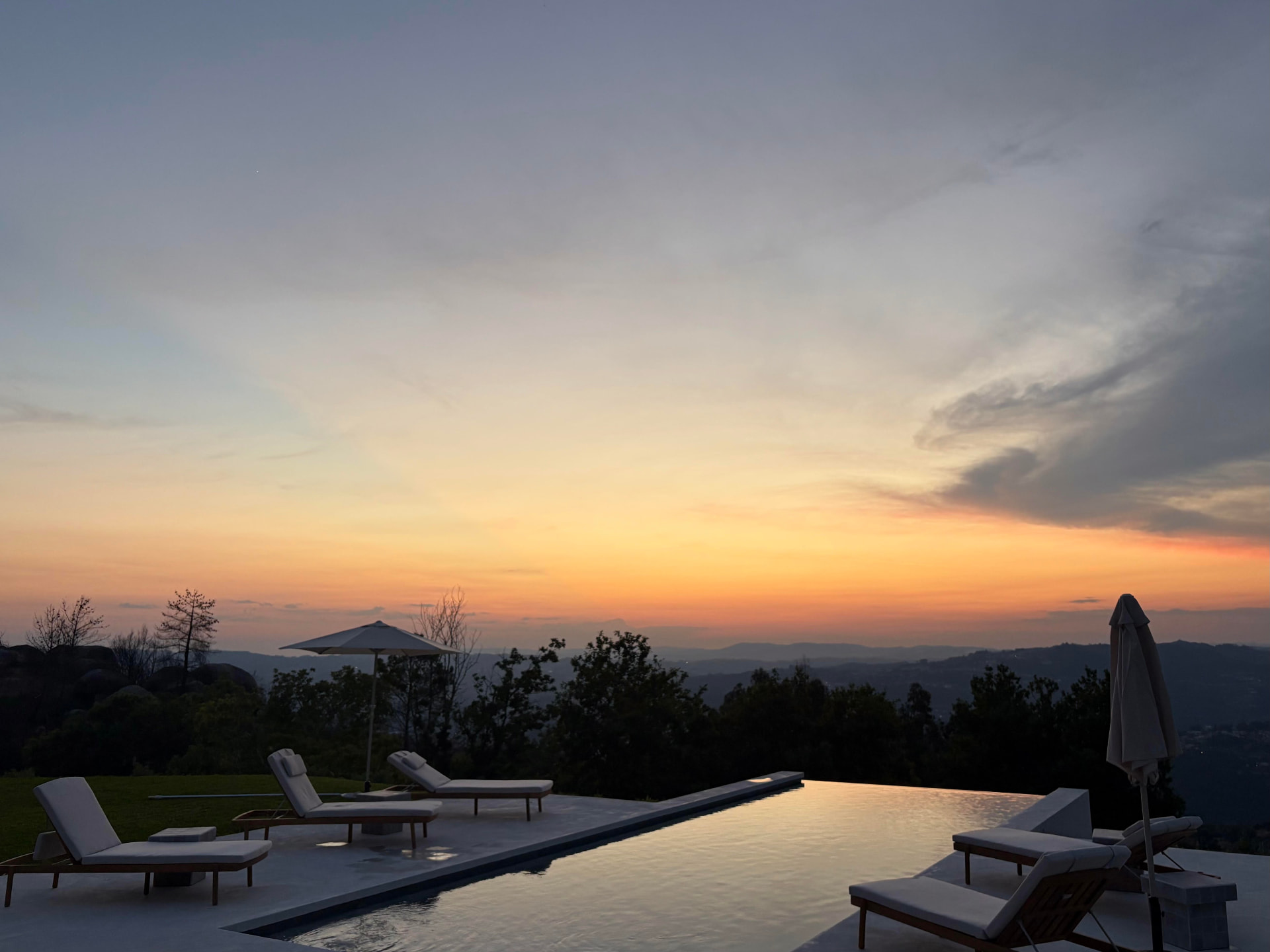Infinity pool and sun loungers at sunset with the valley in the distance