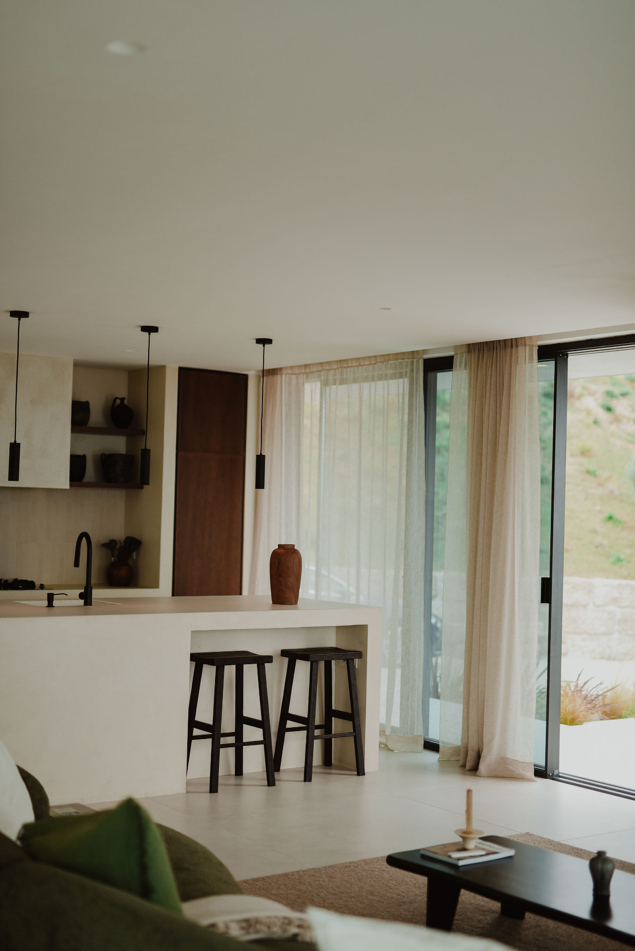 Kitchen island with dark stools, sheer curtains and access to the terrace