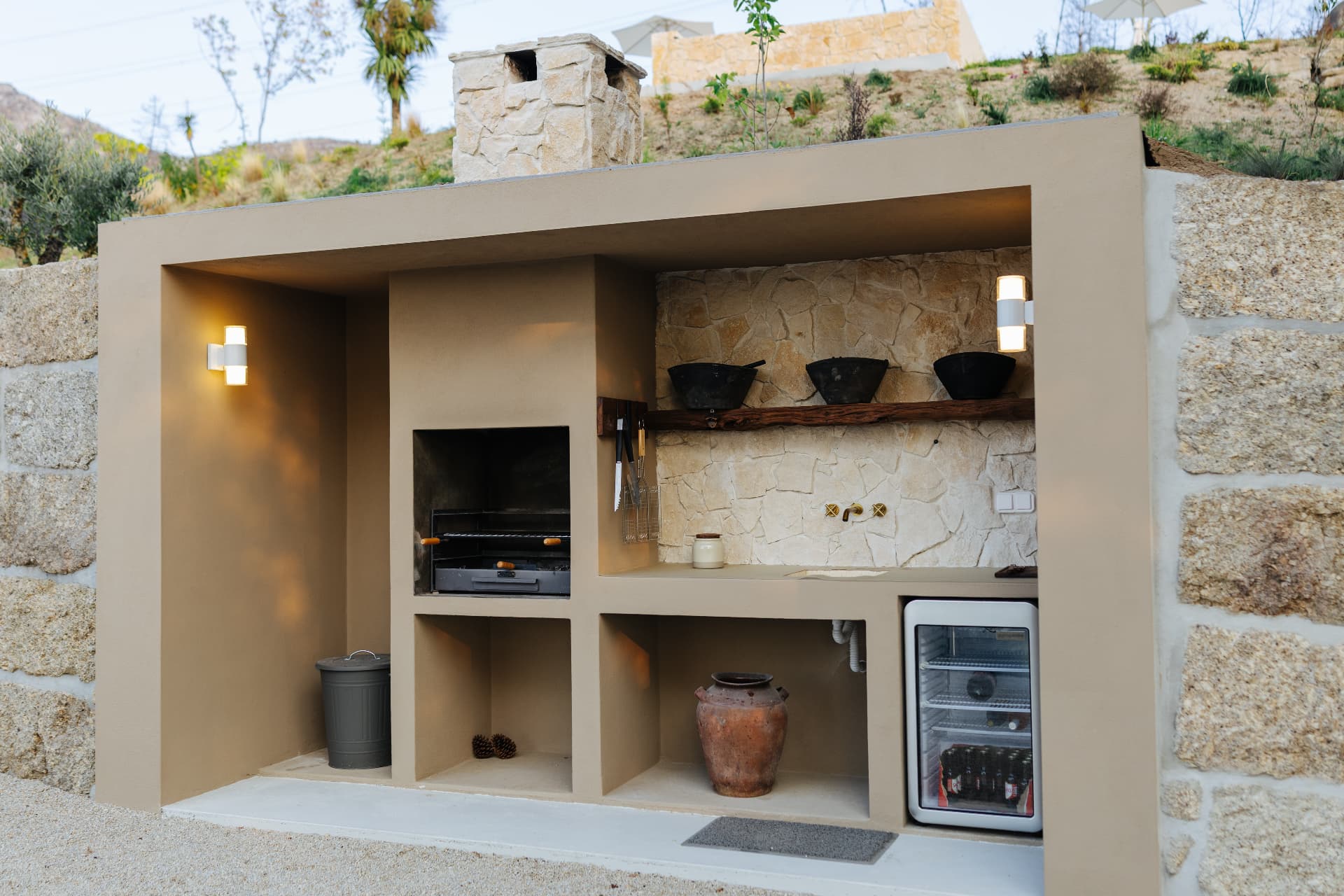 Built-in stone barbecue and outdoor kitchen with warm evening lighting