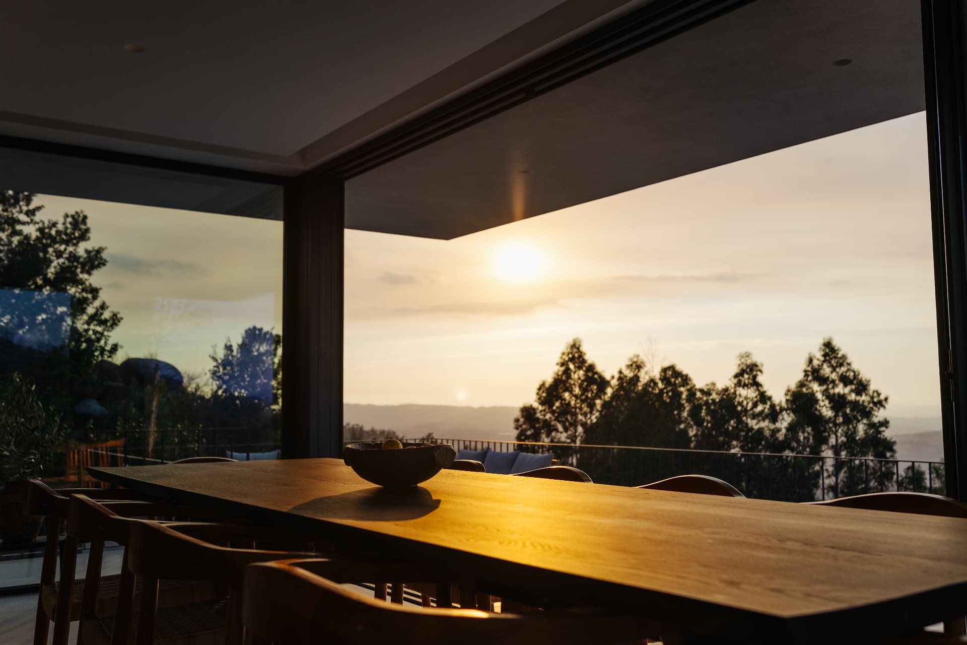 Indoor dining table facing the open glass wall at sunset