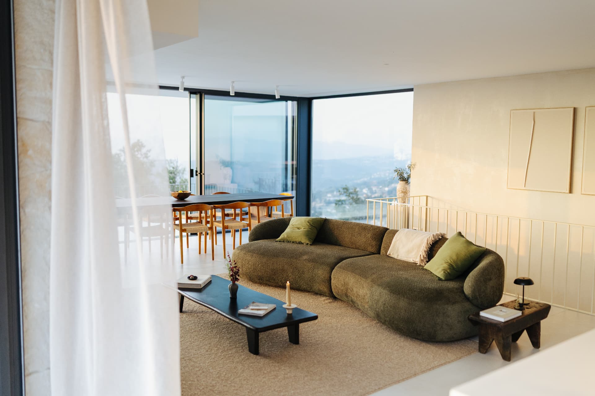 Living room with a curved green sofa, low table and panoramic windows