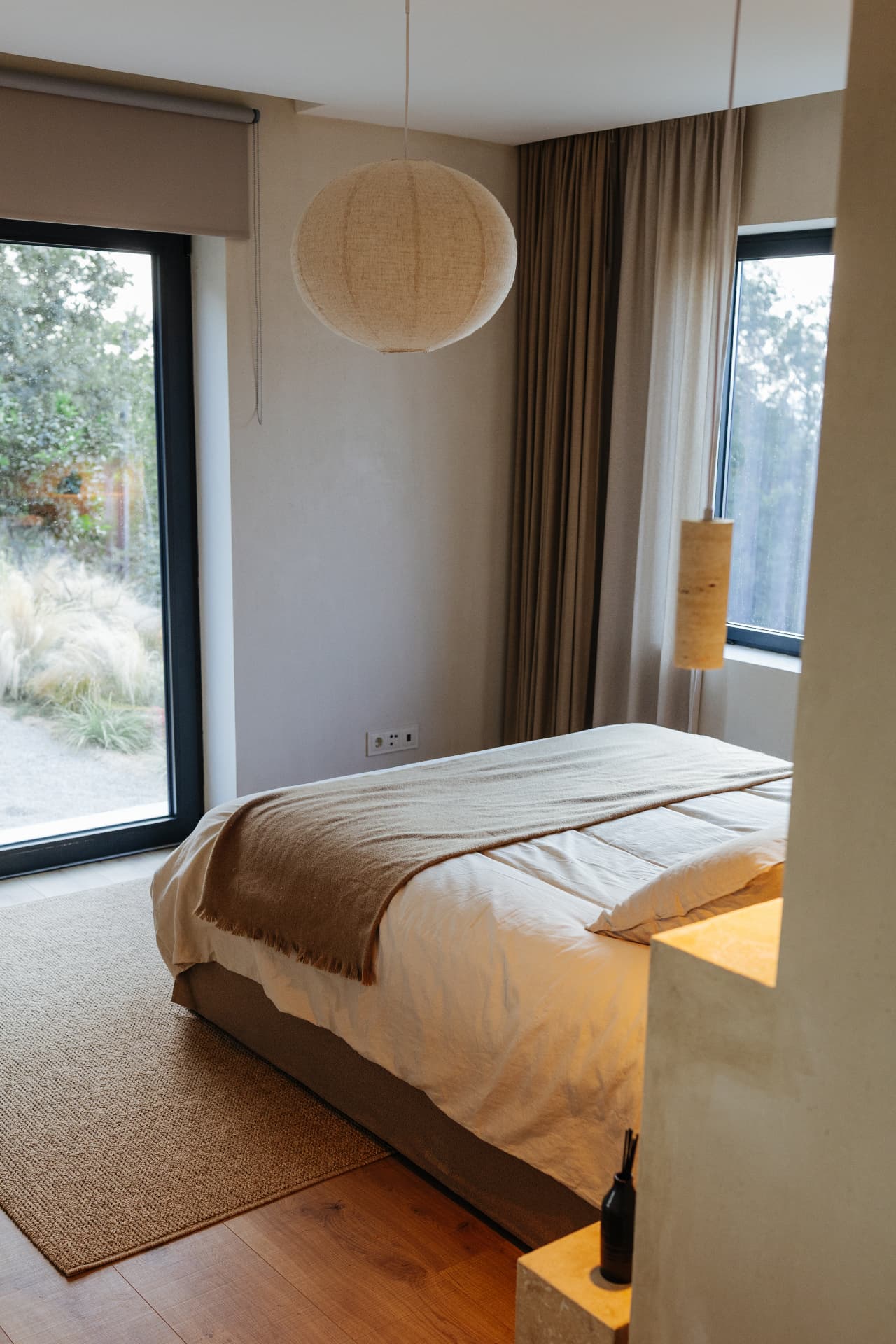 Bright bedroom with floor-to-ceiling windows opening to the garden