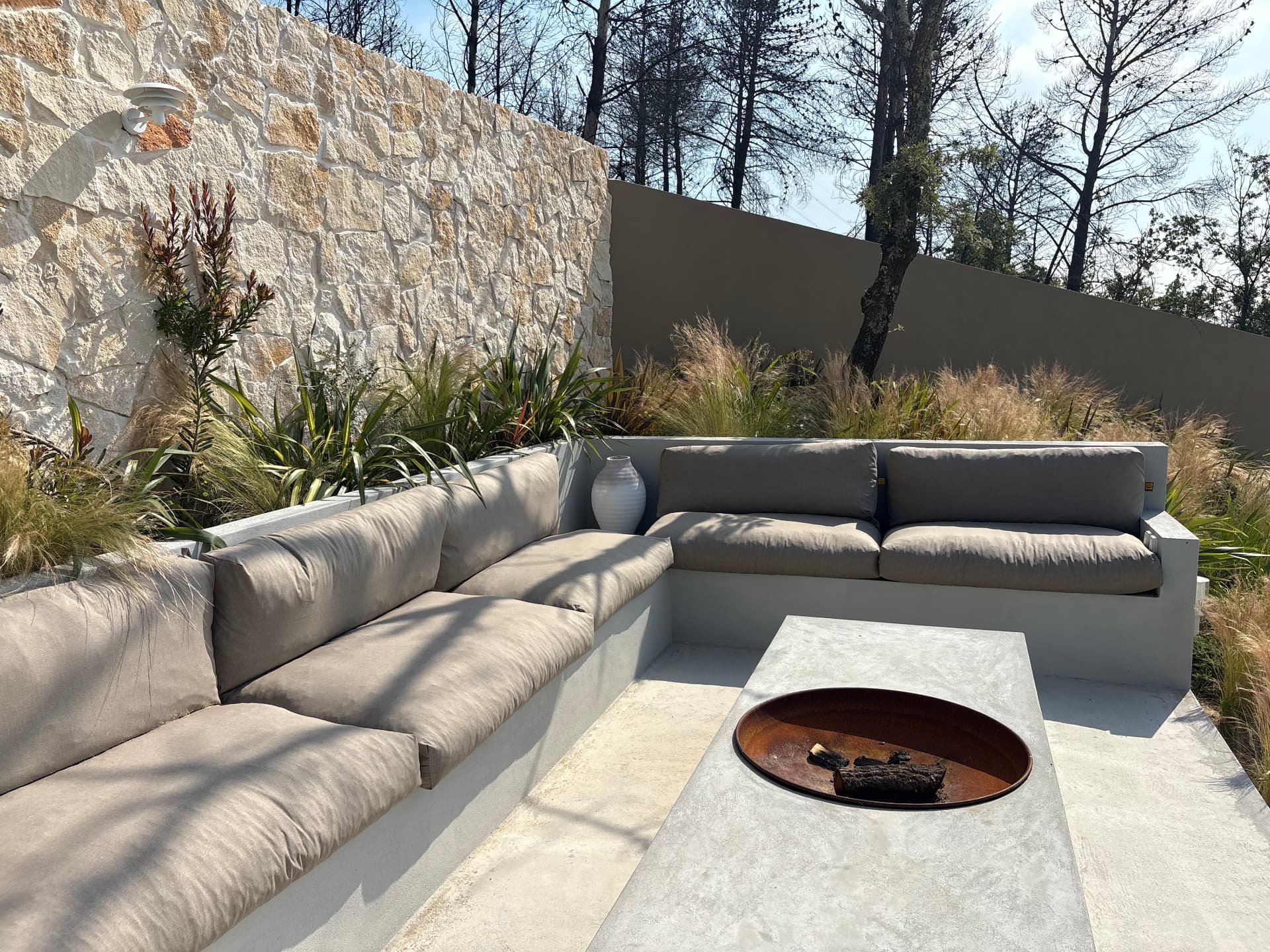 Sunken outdoor lounge with fire pit beside a natural stone wall