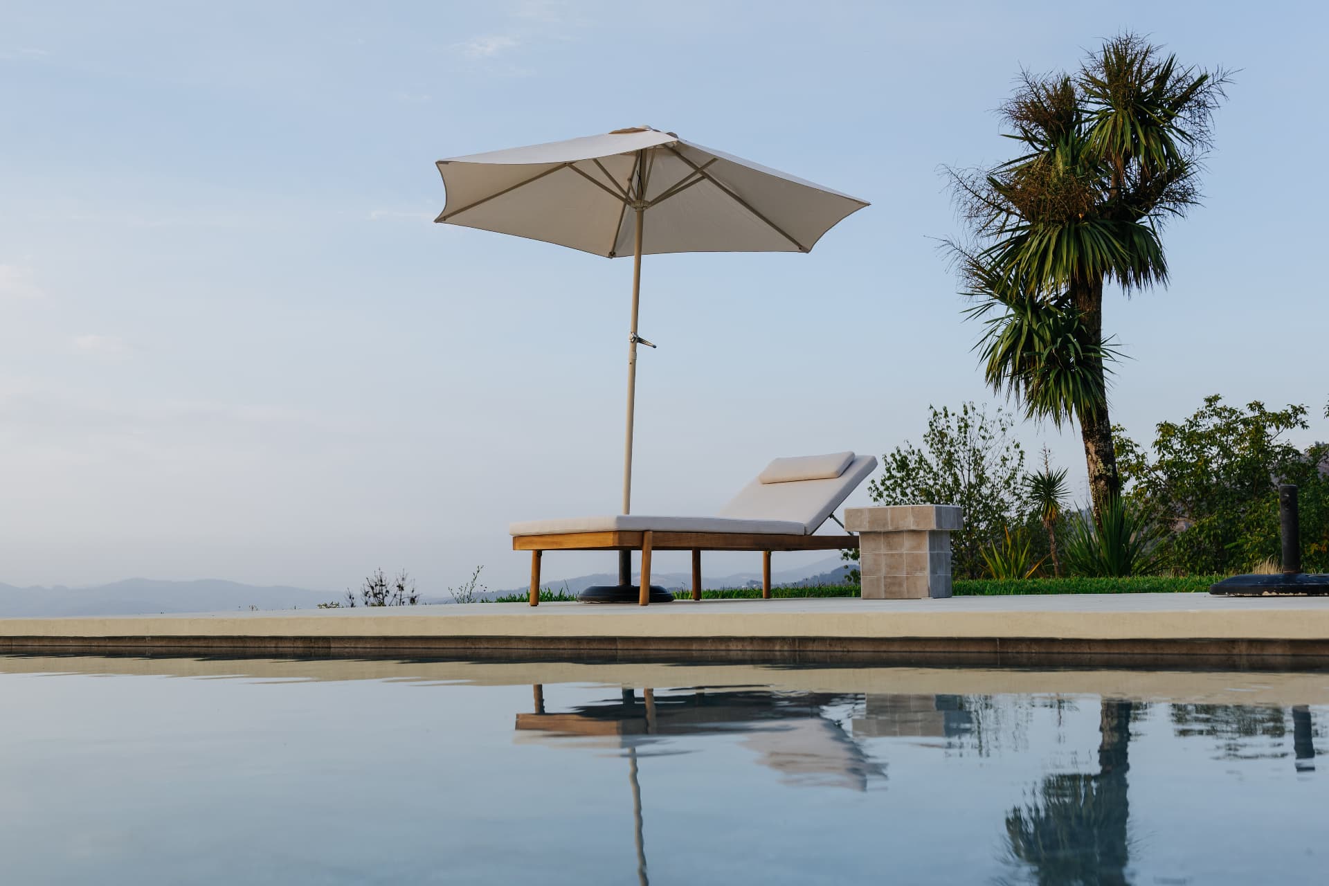 Sun lounger and parasol reflected in the infinity pool
