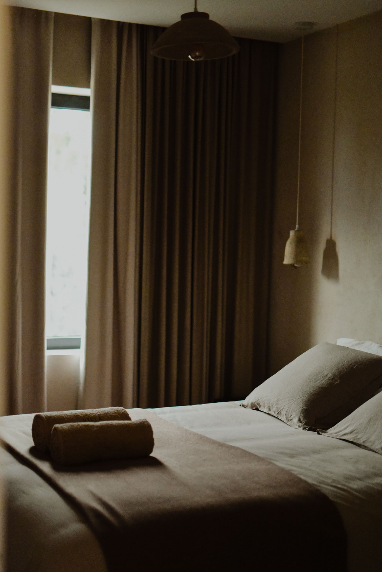 Serene bedroom with linen bedding, rolled towels and soft natural light