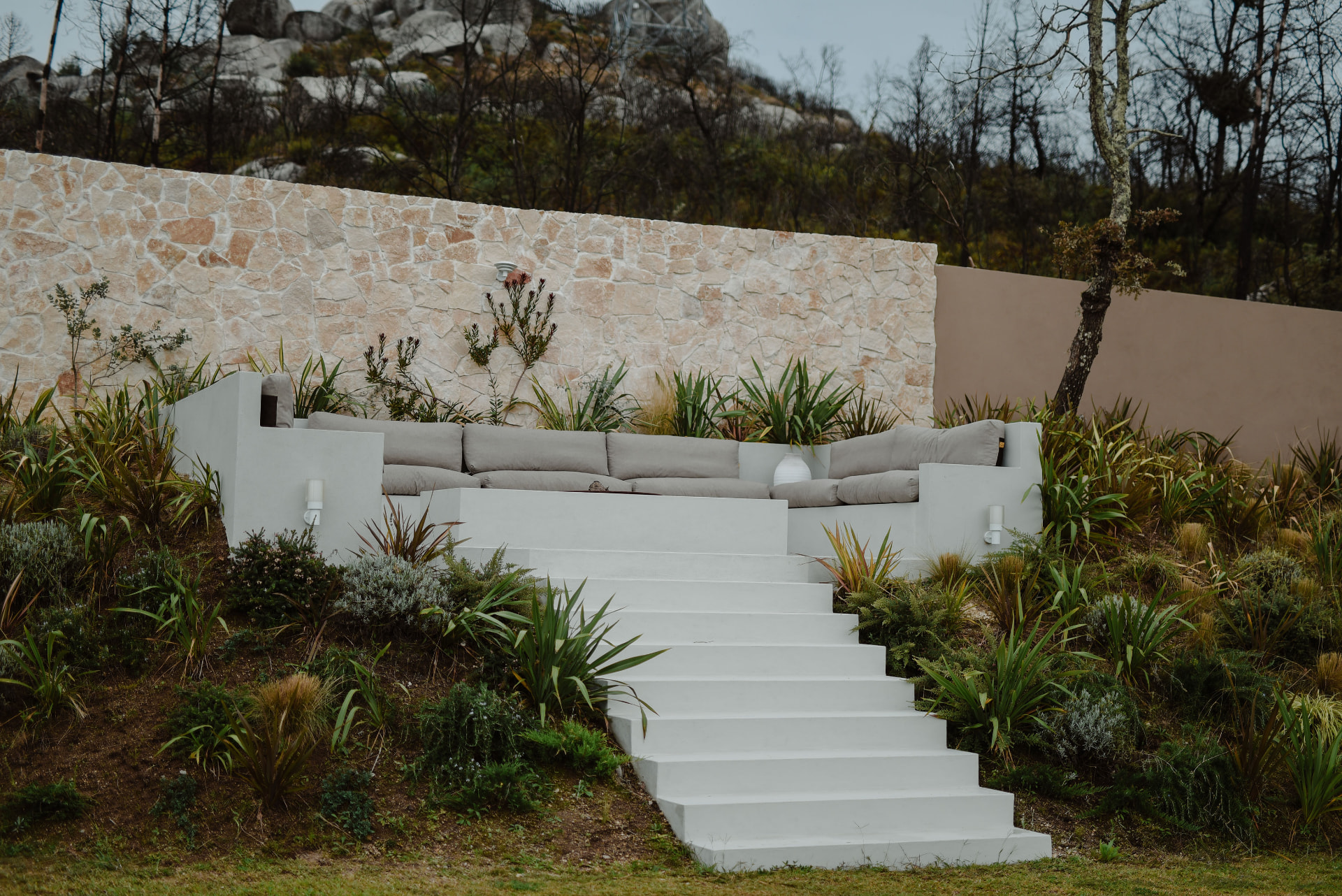 White stone steps leading to a sunken outdoor lounge set into the hillside